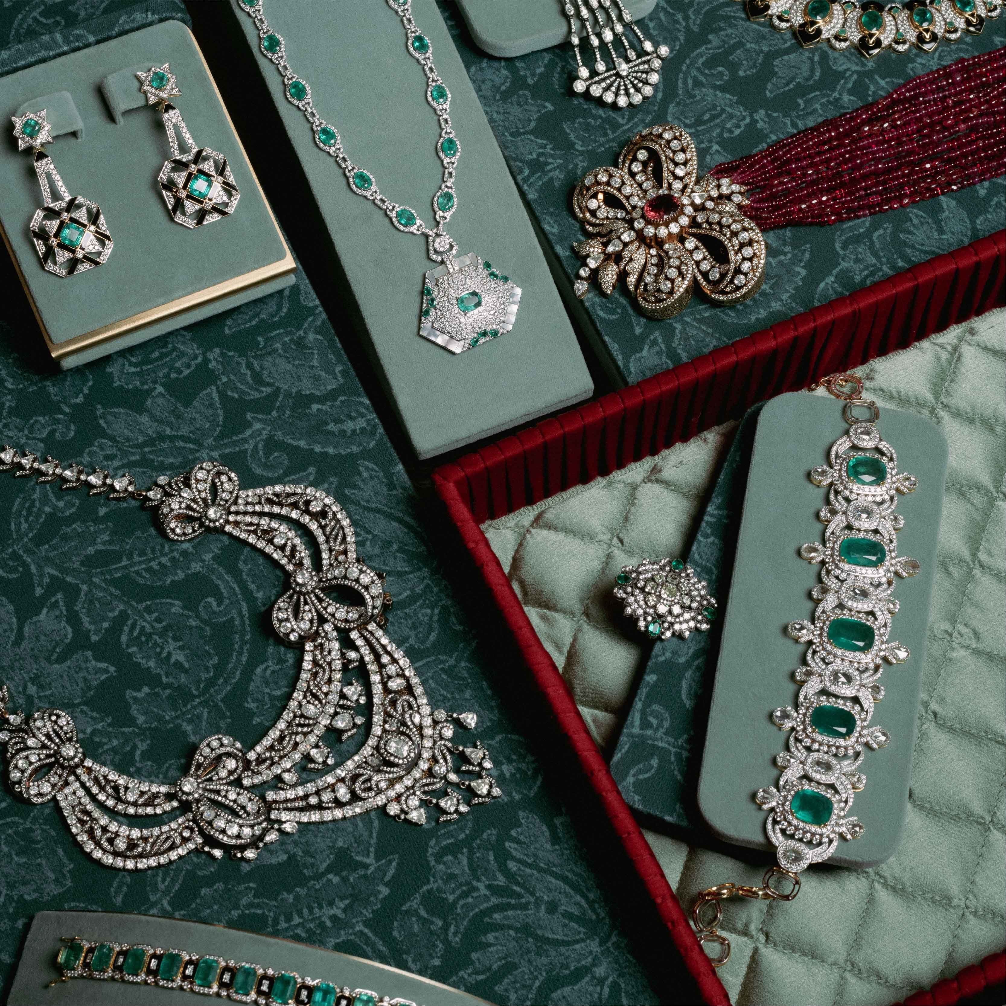 Emerald and diamond jewels arranged across their cases
