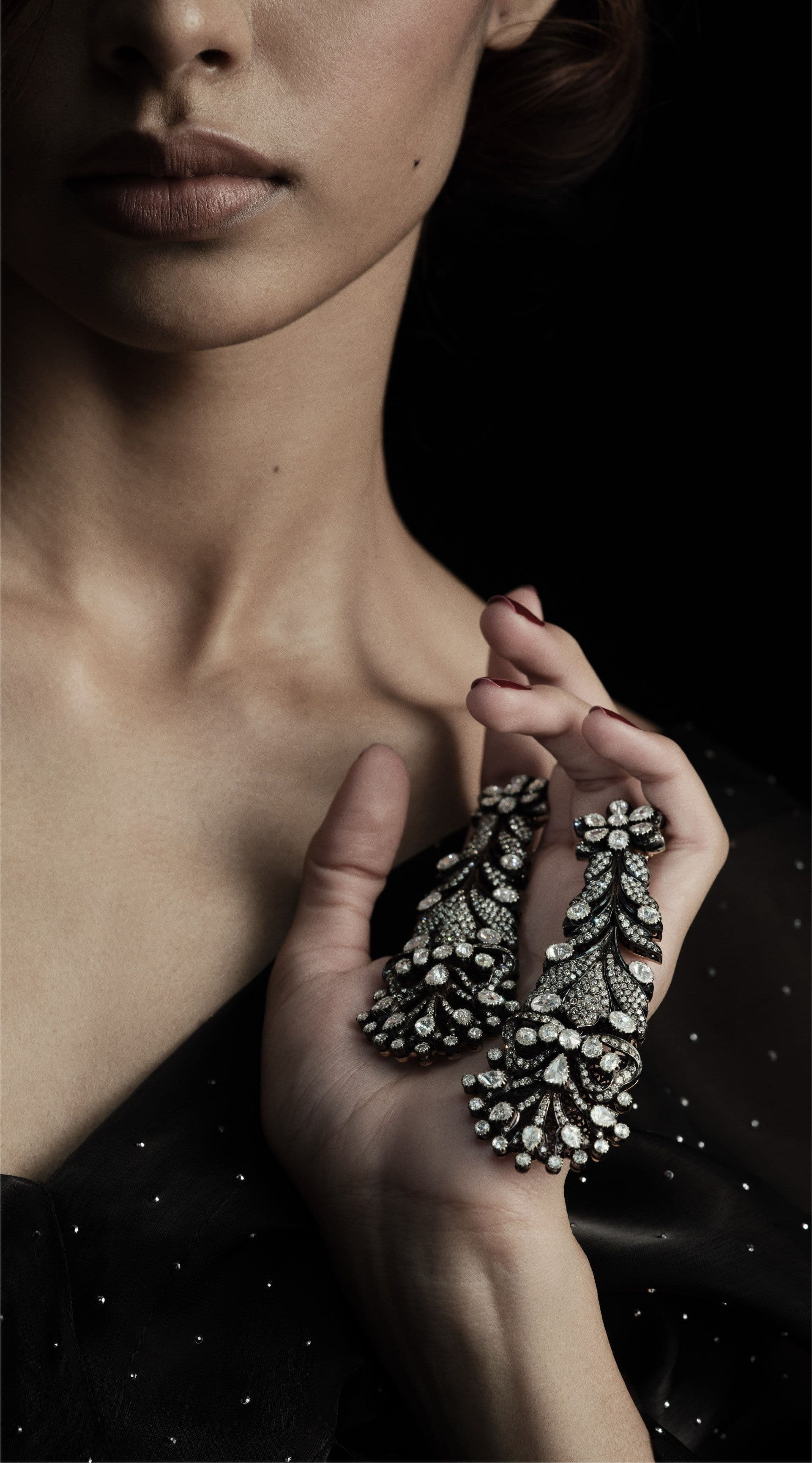 Diamond drop earring held against the shoulder