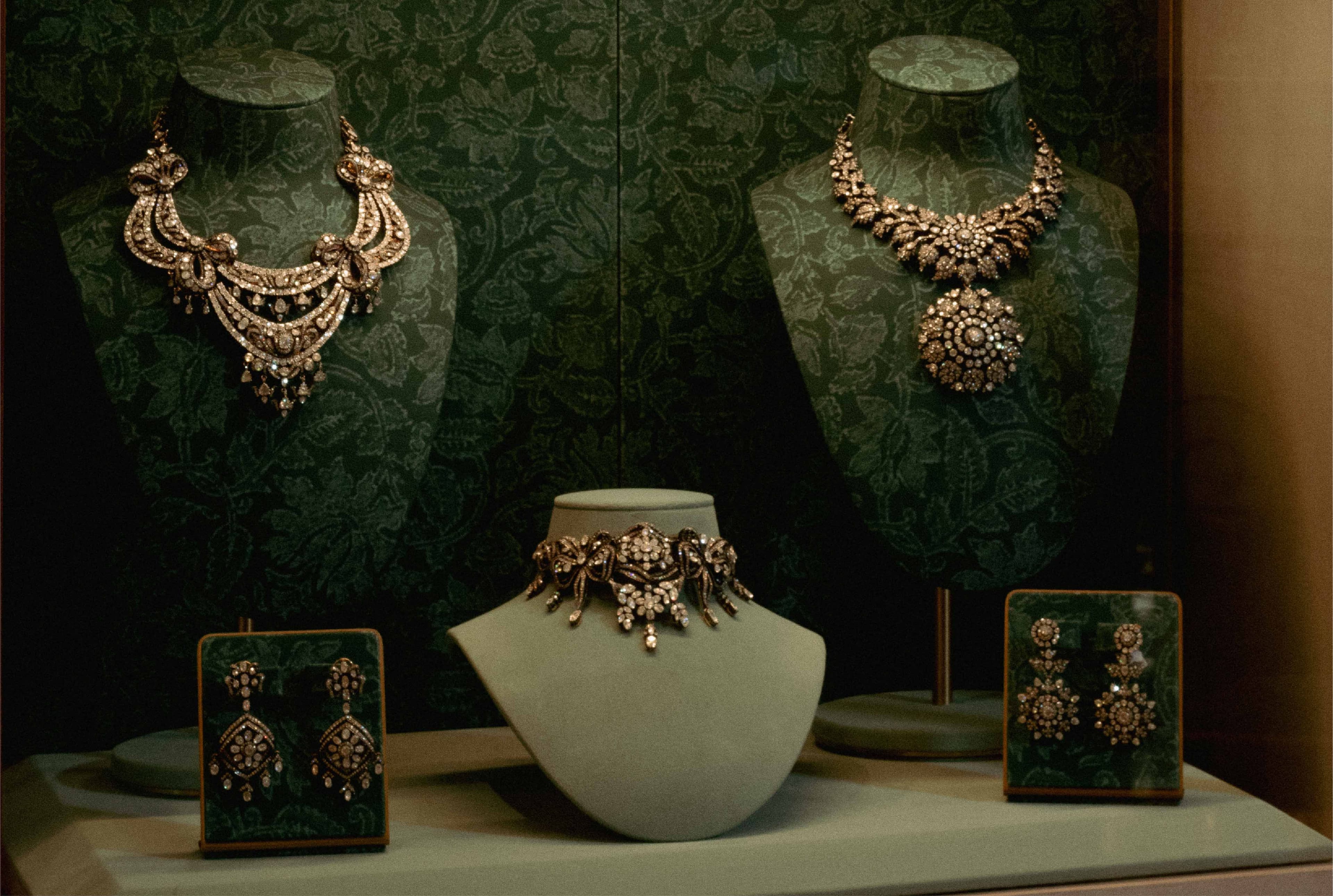 Necklaces and earrings displayed on stands against green velvet