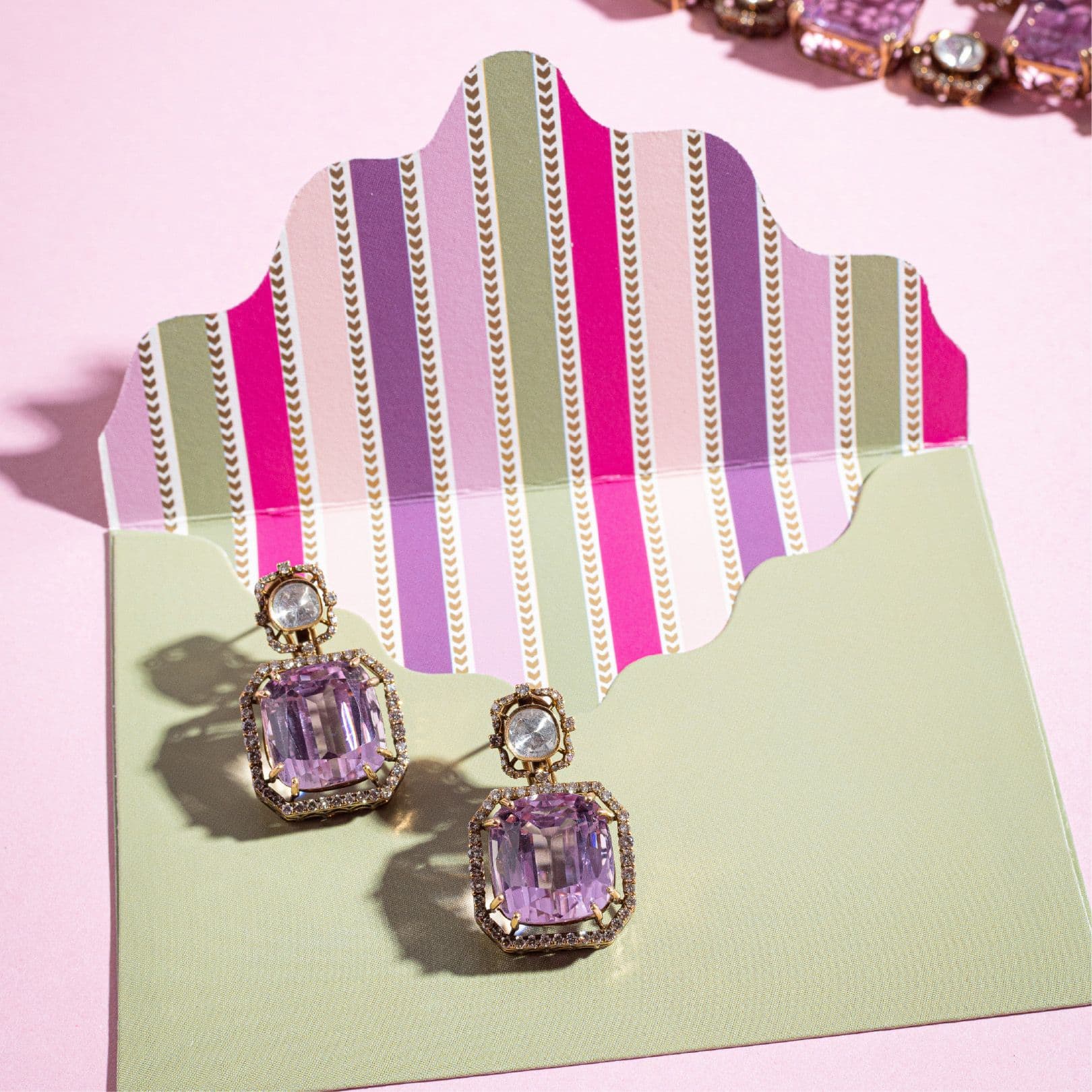 Pink stone earrings on a striped envelope