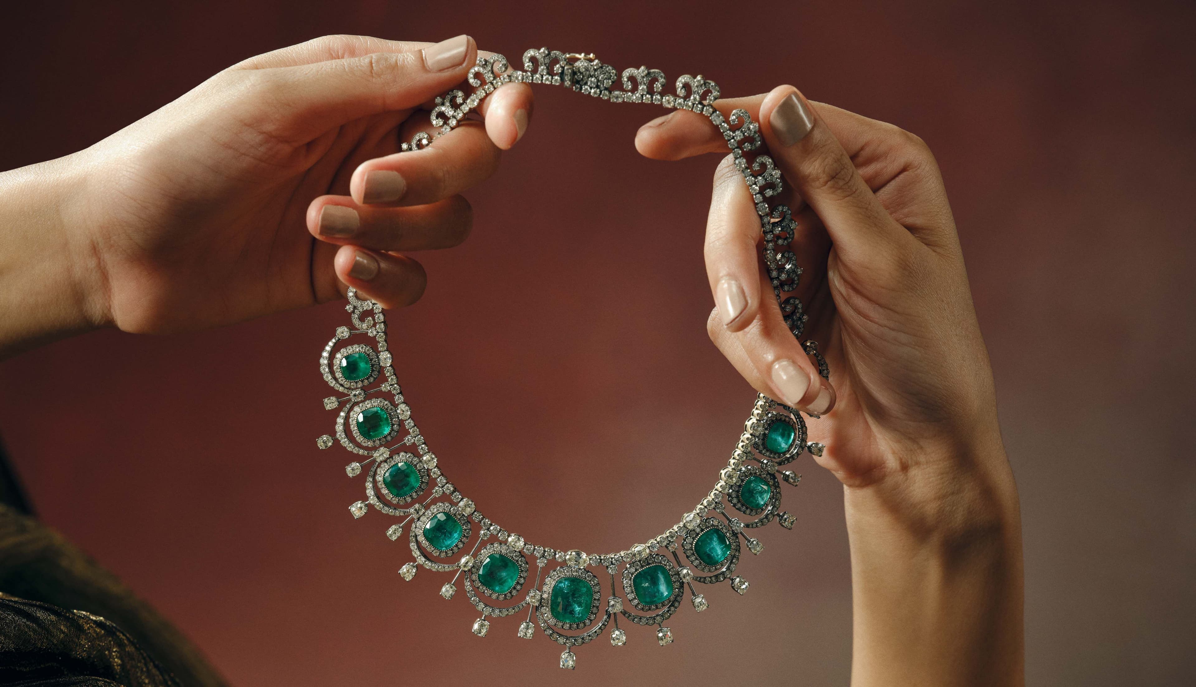 Emerald and diamond necklace held in the hands