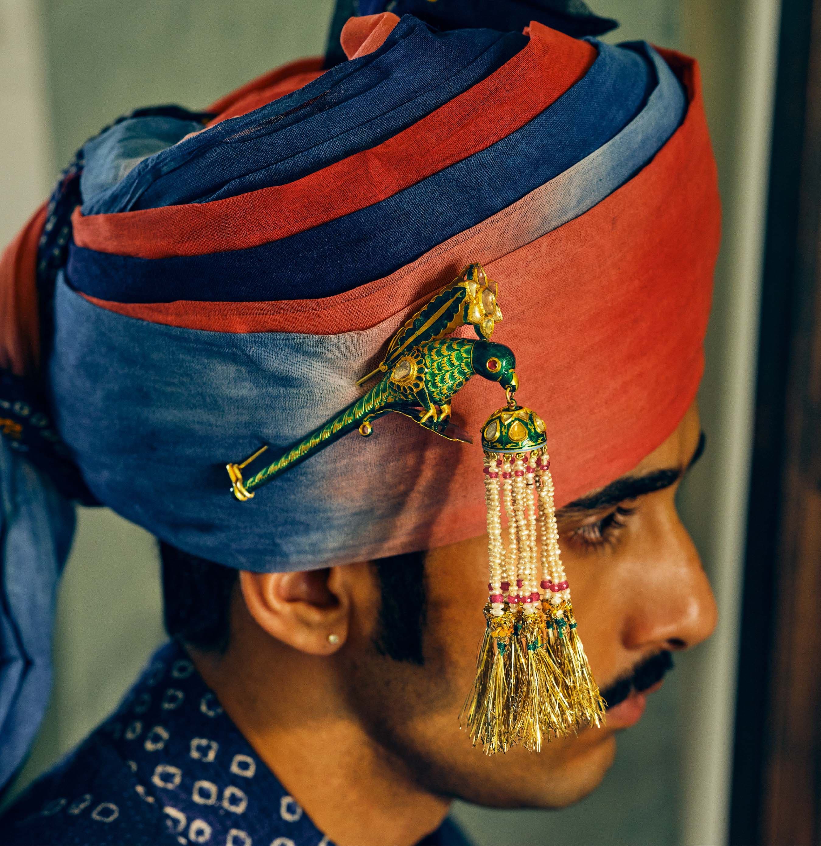Enamelled parrot turra with pearl tassels pinned to the side of a blue and red safa