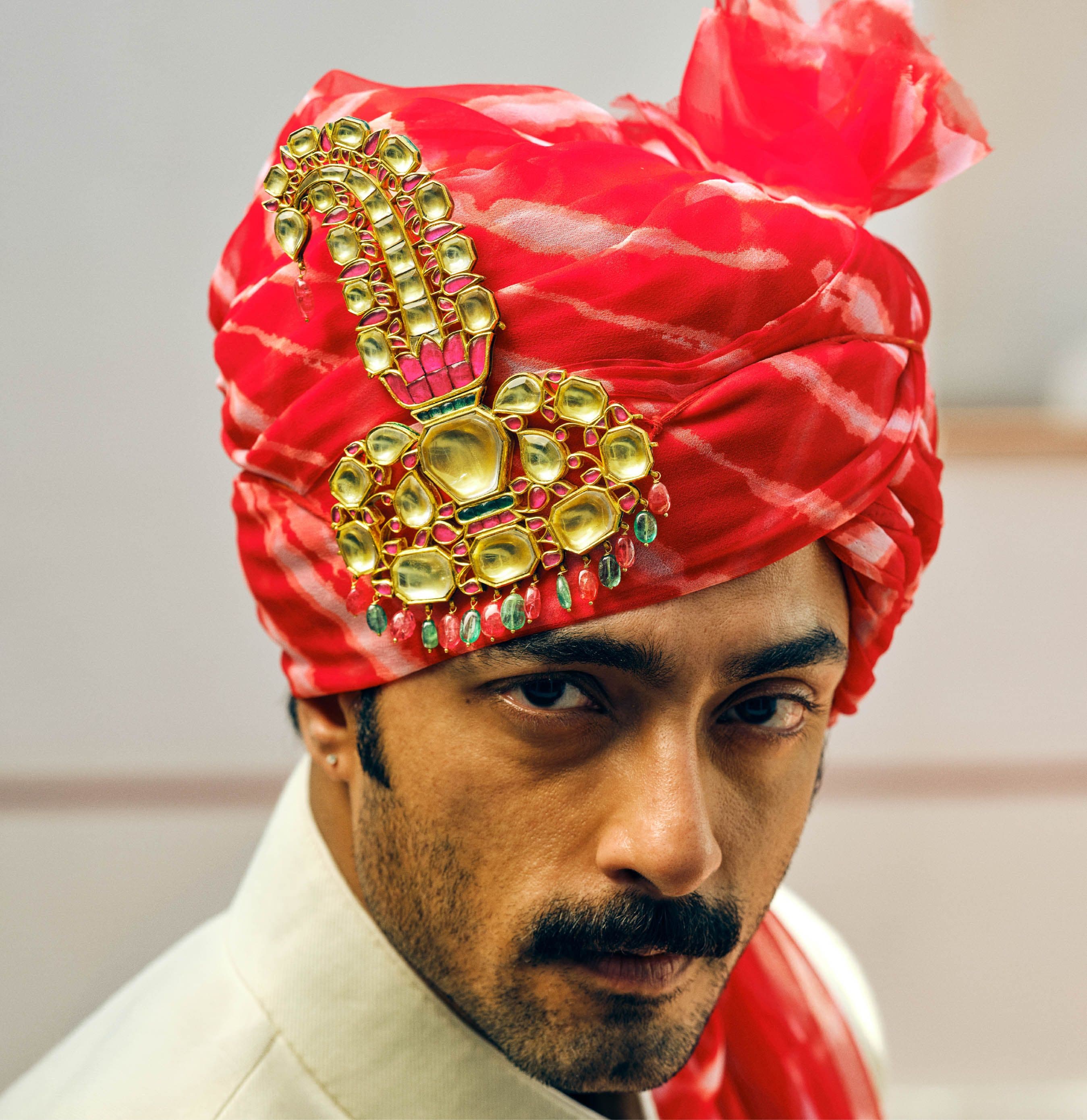 Groom in a red leheriya safa wearing a gold and polki sarpech