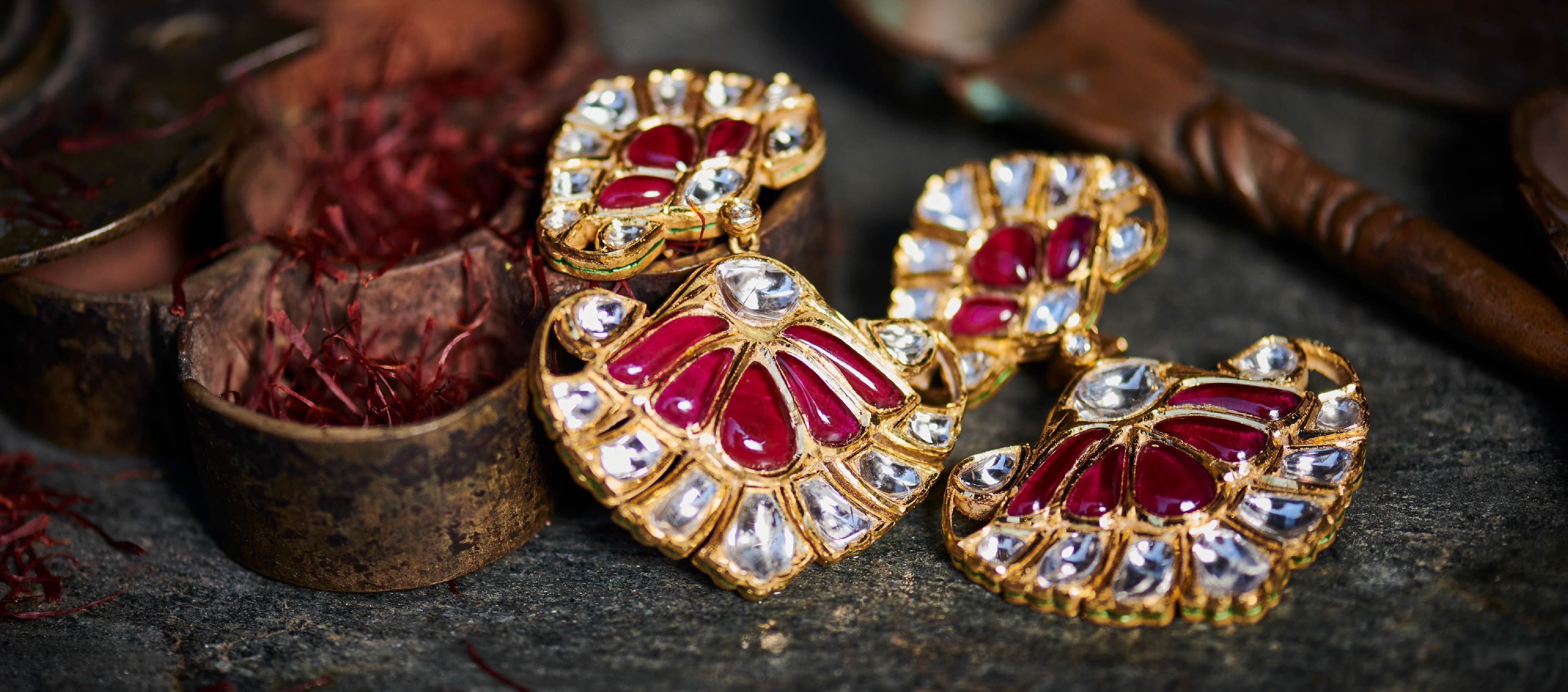 Ruby and polki jadau earrings beside a wooden box of saffron