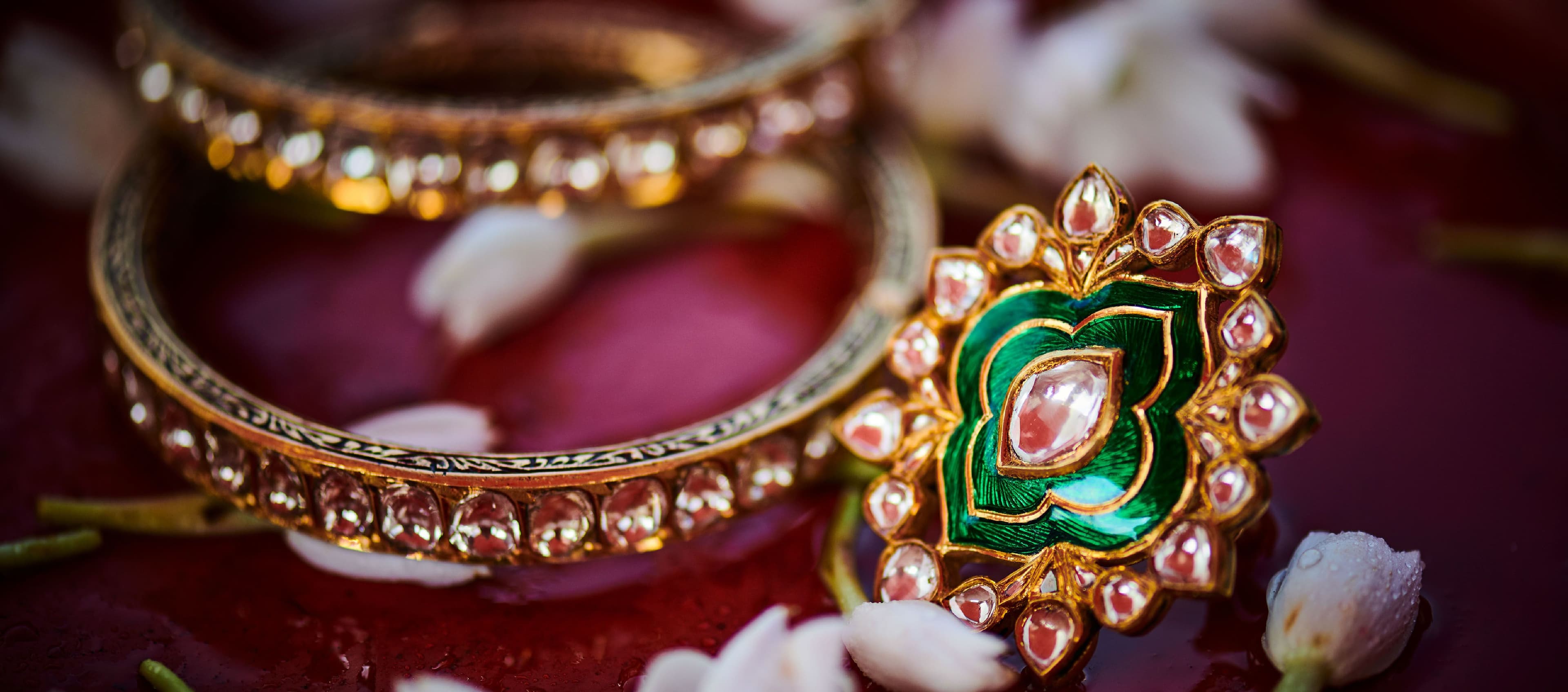 Polki bangles and a green meenakari ring among jasmine petals