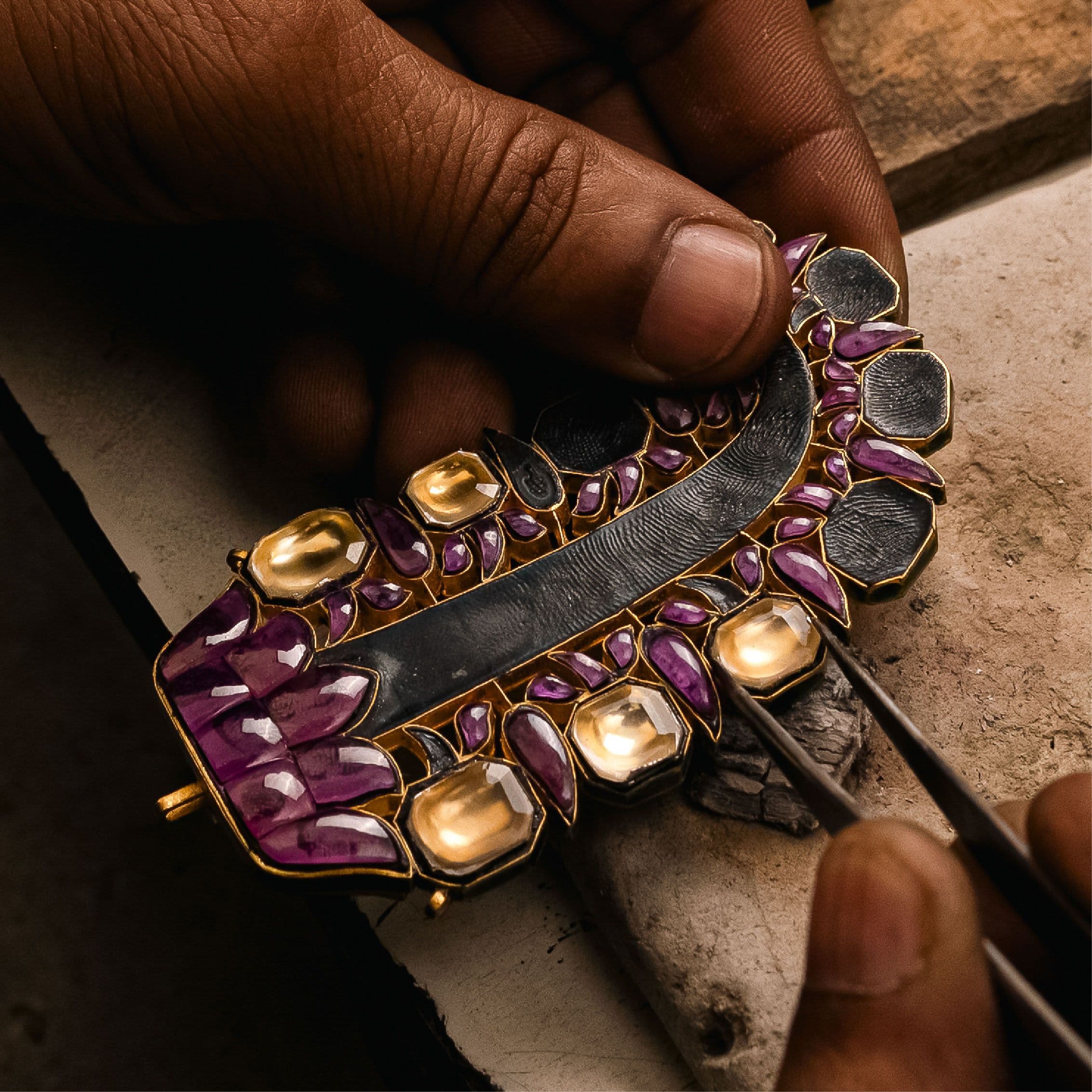 Rubies being set in kundan around a gold-framed pendant